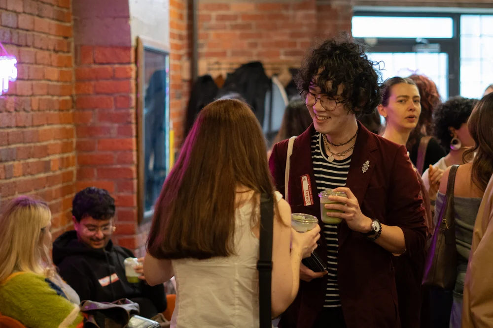 People chatting over drinks in a warmly lit room with exposed brick walls.